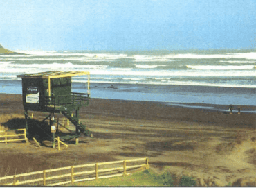Raglan Surf Lifesaving rescue tower on the beach with ocean waves in the background, highlighting the essential lifesaving services at Raglan Beach, New Zealand.